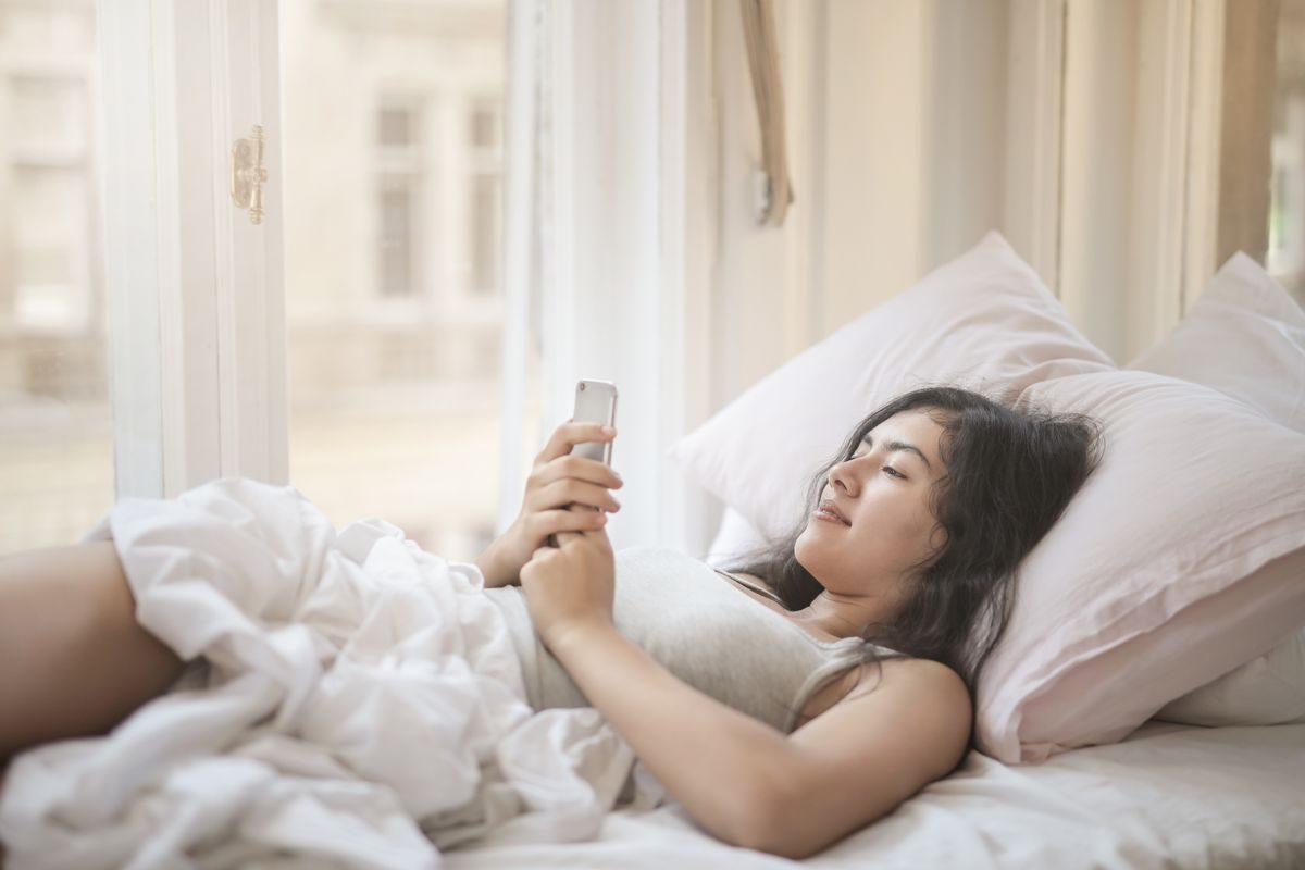 ベッドでスマホを見る女性|通勤も夜もスマホがマンガ喫茶に