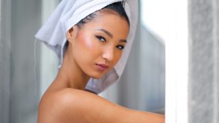 バスタオルを頭に巻いたスキンケア中の女性