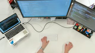 デュアルモニターでコーディングする女性エンジニア