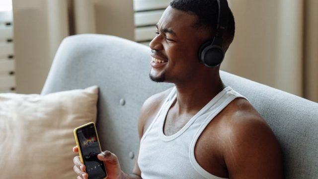 ソファで音楽を楽しむ男性(音楽サブスクイメージ)