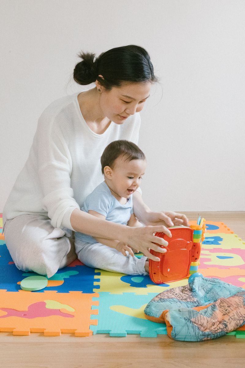 プレイマットの上で教材を使って遊ぶ母親と赤ちゃん