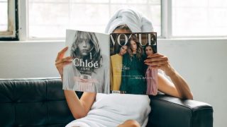 ソファでファッション誌を読む女性|雑誌代が月572円の定額に