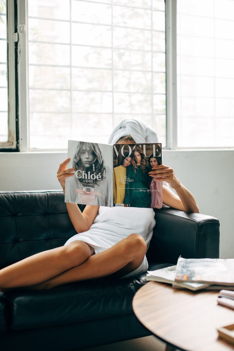 ソファでファッション誌を読む女性|雑誌代が月572円の定額に