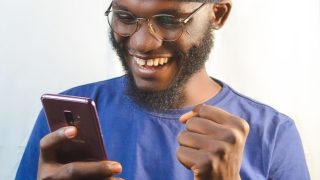 スマホを手に笑顔の男性(契約成立の安心イメージ)