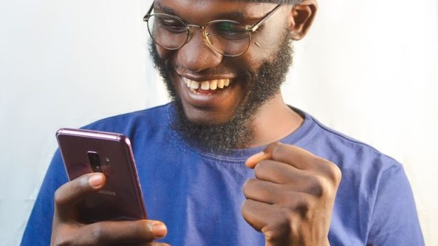 スマホを手に笑顔の男性(契約成立の安心イメージ)
