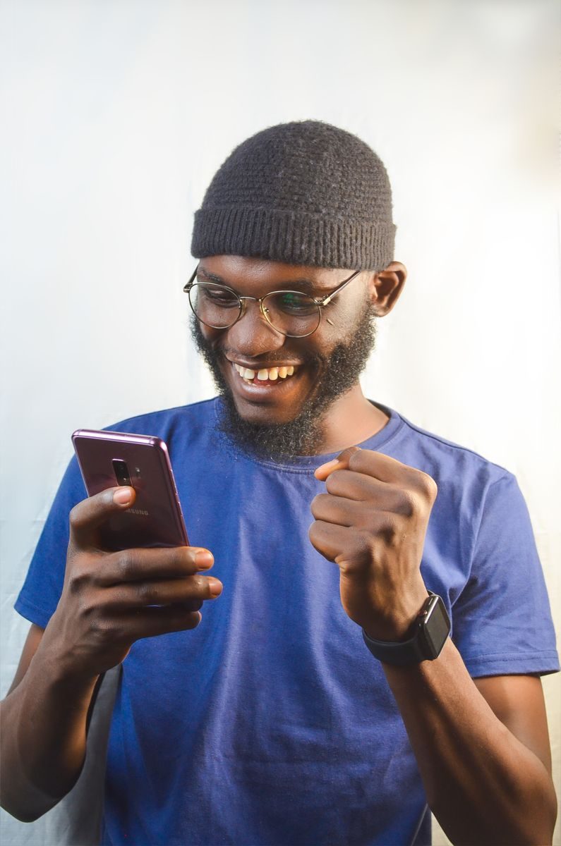 スマホを手に笑顔の男性(契約成立の安心イメージ)