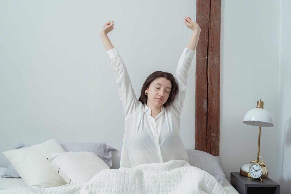 朝すっきりと目覚めて伸びをする女性