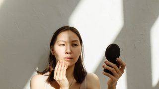 鏡の前でスキンケアする女性