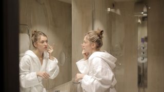 鏡の前でスキンケアする女性