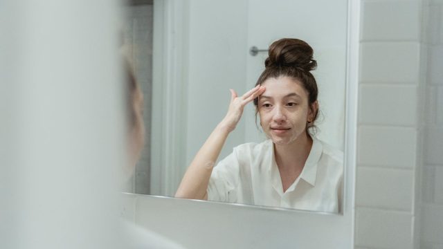 鏡の前でスキンケアする女性
