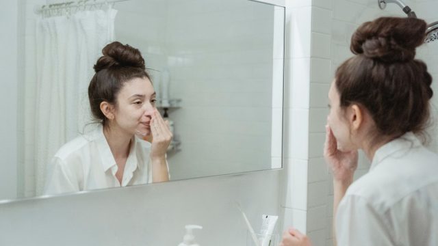 鏡の前でスキンケアする女性