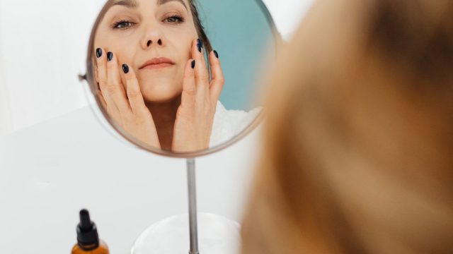 鏡の前でスキンケアする女性